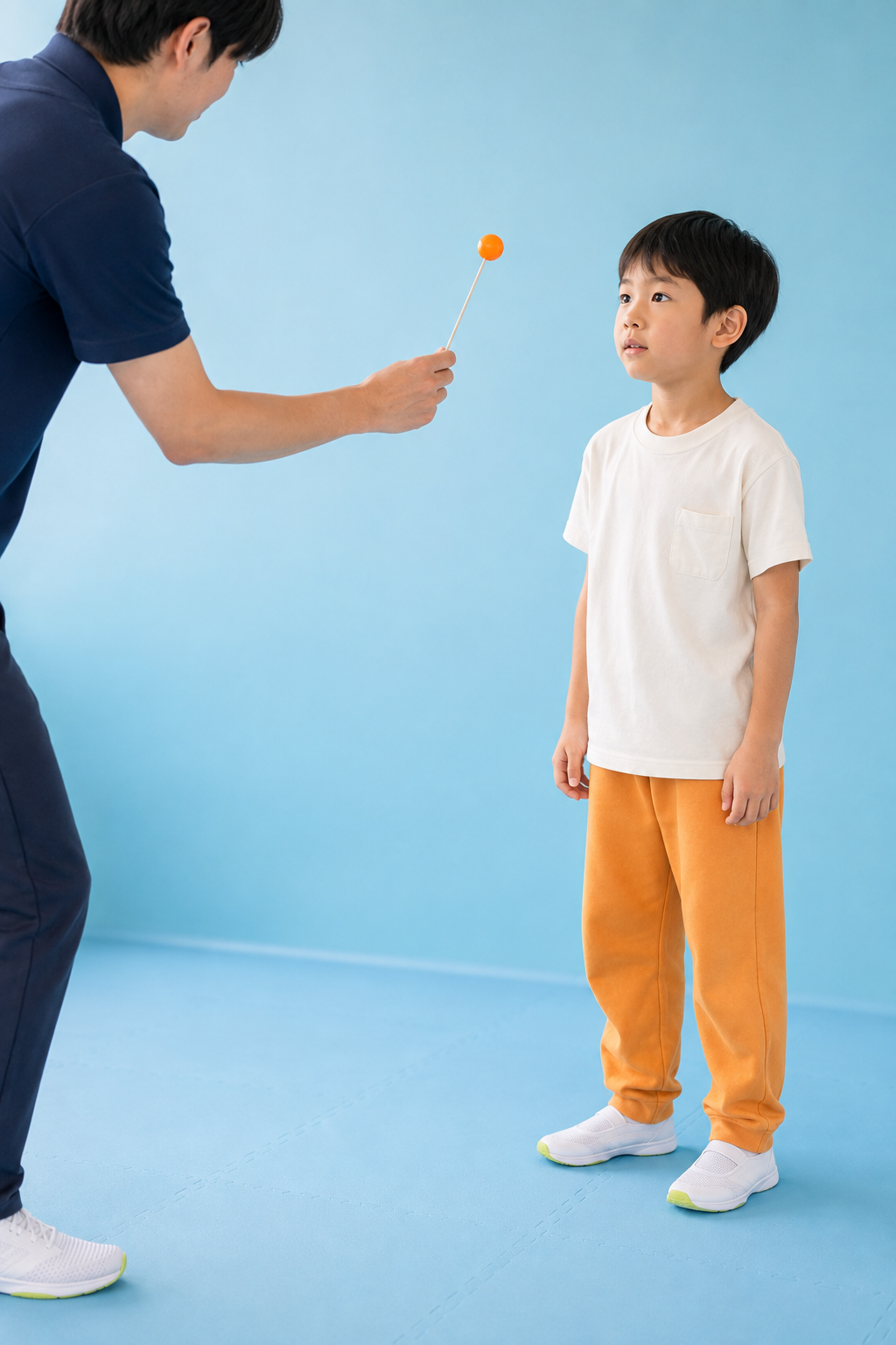 架空の子どもが、指導者の持つオレンジの目印を目で追うトレーニング風景の広告イメージ